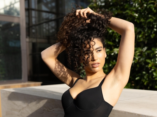 Donna in intimo nero si raccoglie i capelli in alto sicura di sè